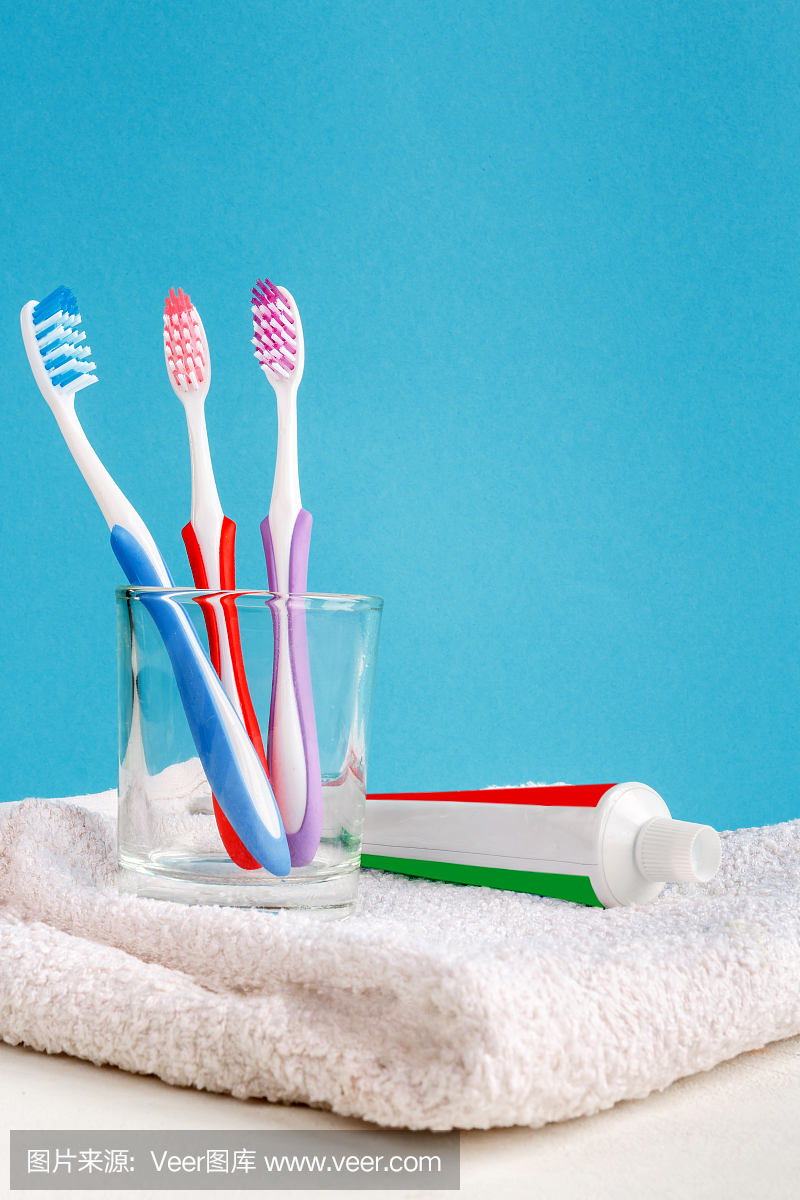 健康的牙齿。杯子里的牙刷,蓝色背景的浴室桌子上的牙膏和浴巾。设计,保健,卫生健康,清新呼吸